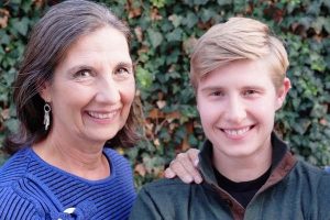 A portrait of Stella and Donna smiling into the camera. Behind them is a green shrub wall.