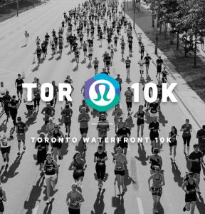 A black and white aerial photo of people running for a marathon on a street with white text overlaid "TOR 10K" in big bold letters with the lululemon logo and with smaller white letters underneath "Toronto Waterfront 10K"