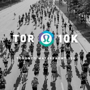 A black and white aerial photo of people running for a marathon on a street with white text overlaid "TOR 10K" in big bold letters with the lululemon logo and with smaller white letters underneath "Toronto Waterfront 10K"