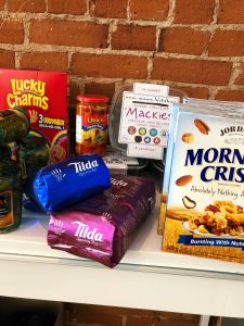 A pantry shelf of packaged food, there's peppers, morning crisp cereal, Lucky charms and coffee bags.