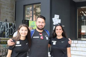 3 people smiling for a photo with their arms around each other. They are all wearing black Nike t-shirts with the Nike swoosh