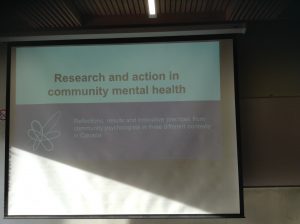 A projector screen that reads "Research and action in community mental health"