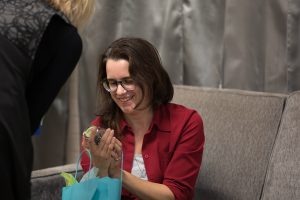 Elizabeth Carey accepting a gift, smiling and looking at an object in their hands.