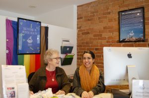 Stella's Place volunteer Liz, pictured with Access Team Member, Nakeesa behind Stella's Place front desk in the café.