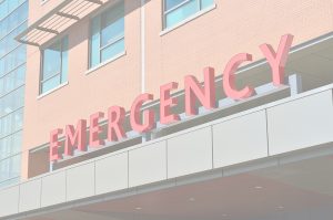 Big letters in red read "EMERGENCY" in a sign outside a hospital